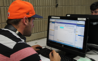 学生戴着橙色棒球帽，在电脑上做作业